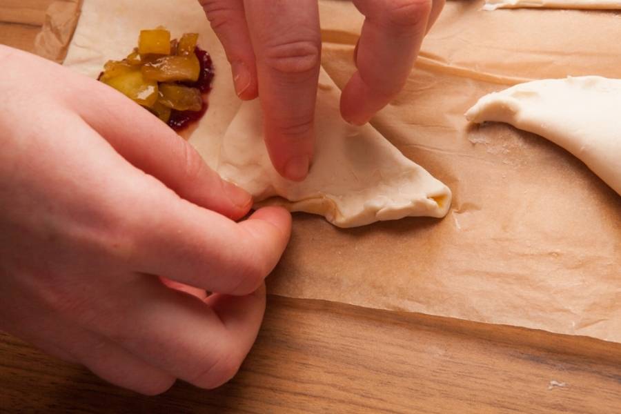 Тесто соединить таким образом, чтобы получились треугольные пирожки, края теста плотно прижать. Если тесто прилипает к пальцам, можно смочить их водой. 