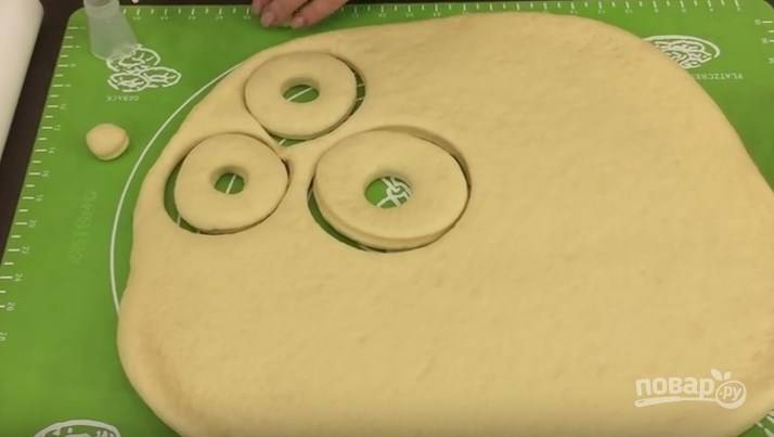 6. Противень застелите пергаментом, сюда выкладывайте заготовки пончиков. Вырезать пончики из теста лучше всего специальной формой, если у вас такой нет - используйте кондитерское кольцо небольшого диаметра. 