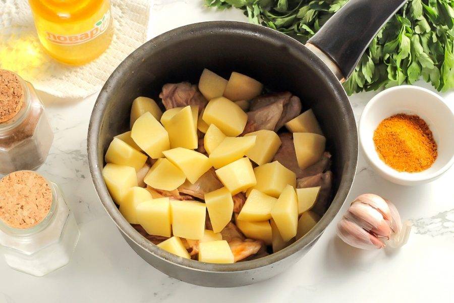 Нарежьте очищенный картофель средними кубиками и добавьте в емкость. Обжарьте вместе с мясом еще 4-5 минут.