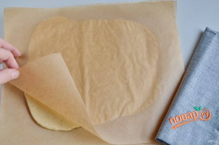 Накройте вторым листом пергамента, скалкой раскатайте тонко. Толщина — 0,5 мм. Второй лист пергамента поможет легко раскатать тесто, чтобы то не прилипло к скалке.