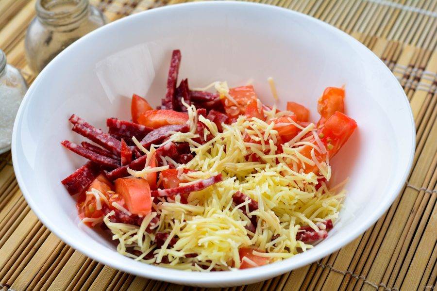 Смешайте в миске все нарезанные компоненты салата - сыр, колбасу и помидоры.