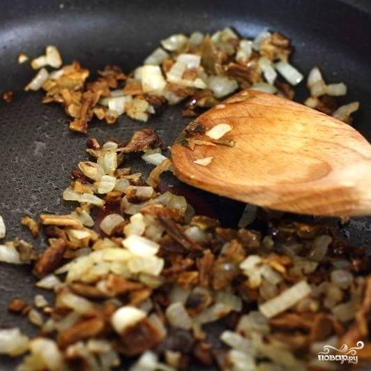 В сковороде разогреваем небольшое количество растительного масла, обжариваем 2 минуты мелко нарезанный репчатый лук, затем добавляем мелко нарезанные грибы и жарим еще 3-4 минуты.