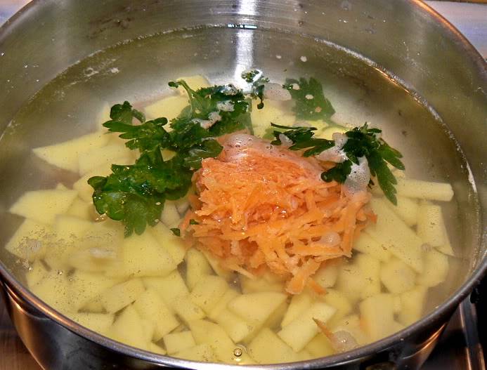 Теперь чистим овощи, картофель нарезаем на небольшие кубики, а морковь трем на крупной терке. Выкладываем овощи в кастрюлю, заливаем водой, добавляем свежую петрушку, солим, ставим кастрюлю на огонь.