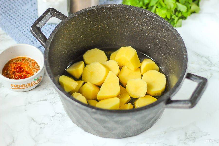 Нарежьте картофель порционными кусочками или кружочками и подсушите бумажной салфеткой. Раскалите в казане растительное масло и выложите в него картофельную нарезку.