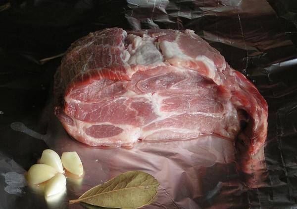 Мясо промойте и обсушите. Поместите свинину на двойной лист фольги. Чеснок очистите.