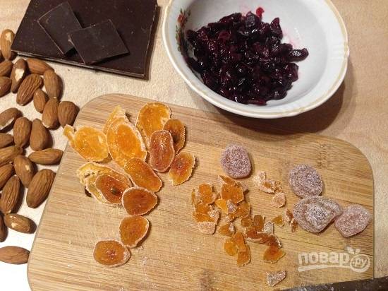 Измельчаем шоколад (ножом, а не теркой, чтобы попадались небольшие кусочки). Цукаты нарезаем маленькими кусочками, не забудьте оставить цукаты и для украшения. Измельчаем орехи.