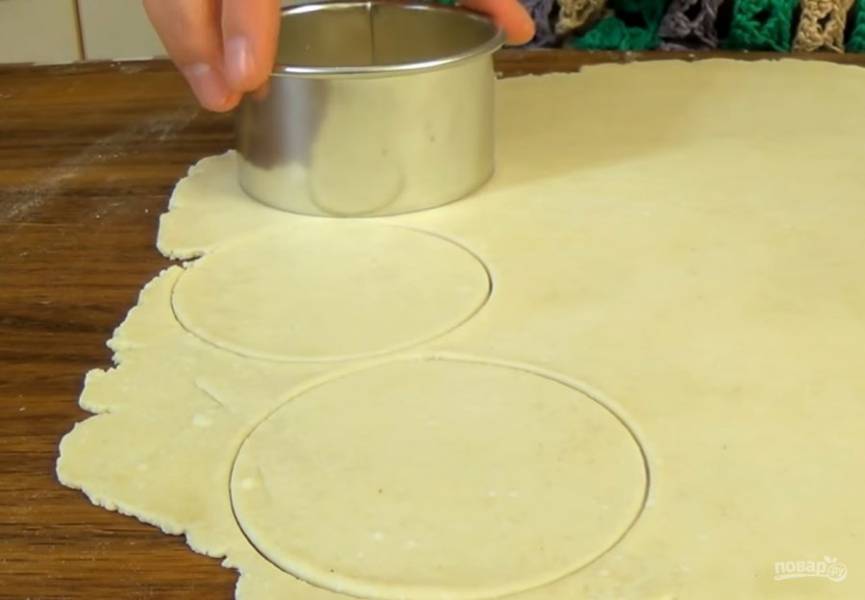 3. Выемкой диаметром 8 см вырежьте кружочки. Сформируйте печенье: обмокните круг теста с одной стороны в сахар с корицей, сложите его вдвое. Затем снова окуните одну сторону печенья в сахар и сложите вдвое. 