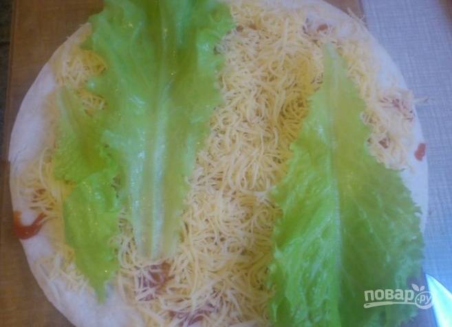 2. Промазываем развернутый лаваш кетчупом, после чего выкладываем  на него натертый сыр, нашинкованный соломкой свежий огурец и листья салата.