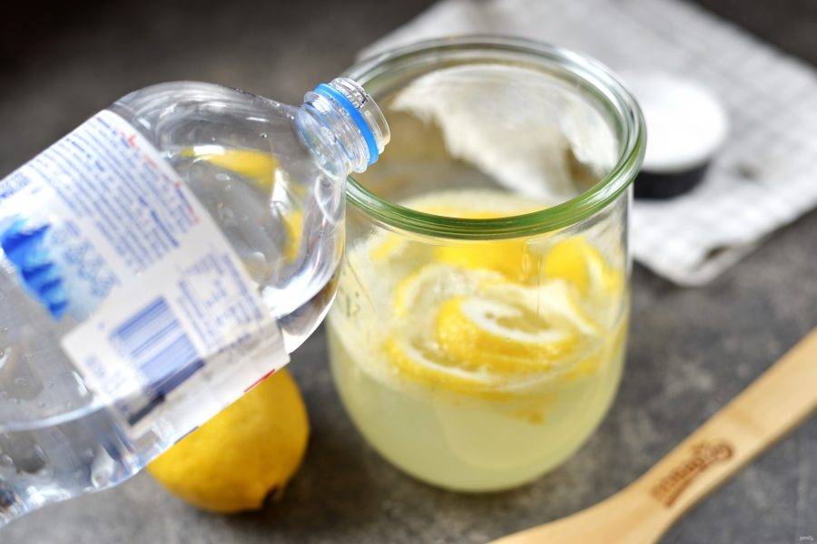 Перелейте лимонный сок с мякотью в большую емкость, порежьте оставшийся лимон тонкими ломтиками. Долейте лимонад доверху газированной водой.  