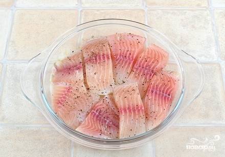 В форму для запекания в один слой выложите рыбу, порезанную порционными кусочками, немного посолите и поперчите.