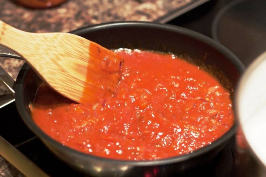 3. Пока рыбный суп варится, разогрейте на сковороде оливковое масло и обжарьте мелко нарезанные фиолетовый лук и чеснок (около 5-8 минут на среднем огне). После добавьте консервированные помидоры и тушите всё вместе 20 минут.