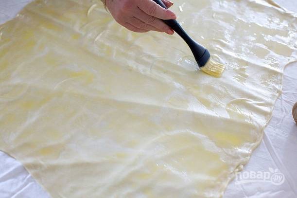 7. Растопите оставшееся масло и остудите. С помощью кисточки промажьте тесто примерно половиной масла. 