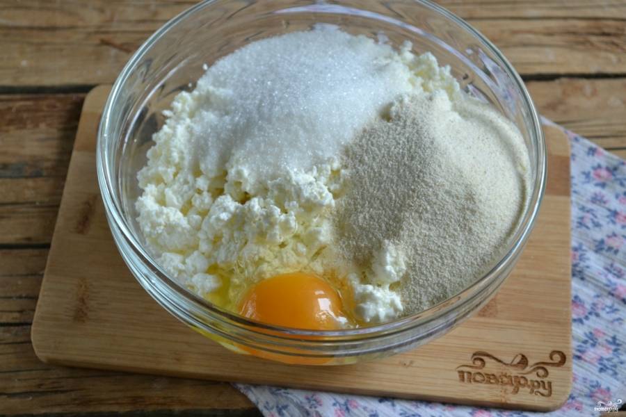В глубокой миске смешайте творог, яйцо, сахар, разрыхлитель и манку. Хорошенько все перемешайте вилкой.