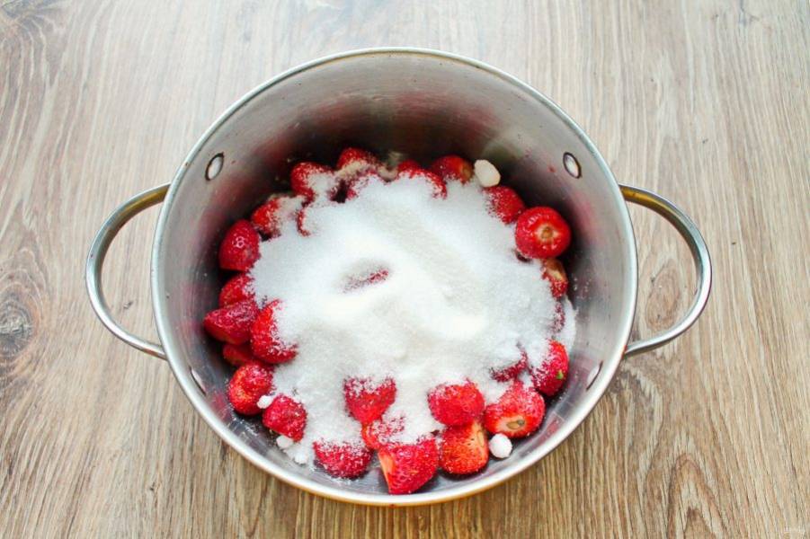 Клубнику переберите, сполосните и дайте воде полностью стечь. Удалите у ягод хвостики, выложите в глубокую кастрюлю с толстым дном или таз и засыпьте их сахаром.