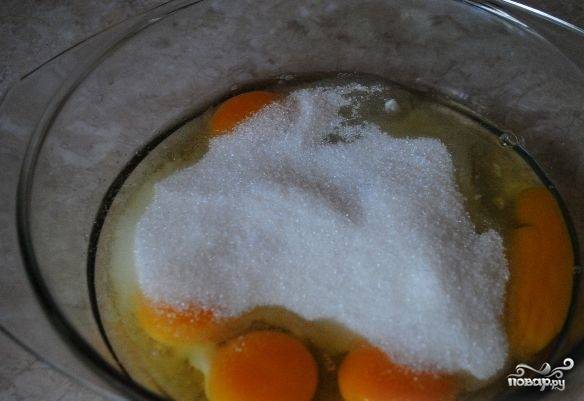 1. Перед тем, как приготовить бисквит без миксера, достаньте из холодильника яйца. Подождите, пока они станут теплыми. Затем вбейте их в миску и всыпьте сахар песок. Яйца с сахаром перетирайте вручную с помощью ложки на протяжении получаса. Каждые 3 минуты в смесь доливайте столовую ложку воды. 