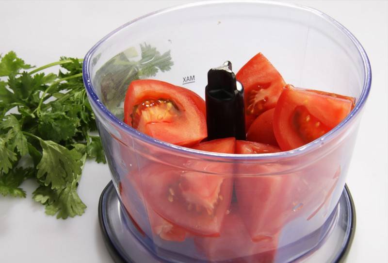 Теперь нарезаем помидоры на небольшие части и выкладываем их в чашу блендера, часть свежей зелени отправляем туда же, измельчаем все до однородной воздушной массы. 
