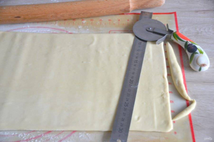 Подровняйте по линейке края теста с обеих сторон, срежьте неровности ножом для пиццы или обычным ножом. 