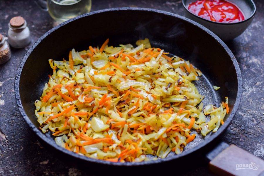Сковороду прогрейте и добавьте масло, выложите капусту и морковь, жарьте 5-7 минут, до румяности.