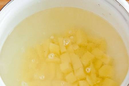 Налейте в кастрюлю 2 литра воды, поставьте на огонь и доведите до кипения. Картофель помойте, очистите, порежьте кубиками и положите в кипящую воду.