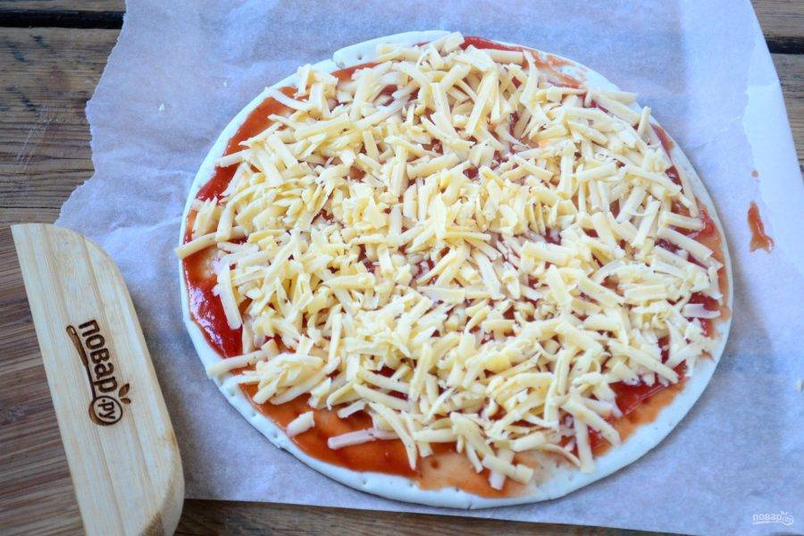 Твердый сыр натрите на крупной терке, щедро присыпьте им основу для пиццы. Сыра должно быть много, он придаст готовой пицце невероятный вкус, и вы забудете, что в ней нет ни мяса, ни колбасы, ни грибов.
