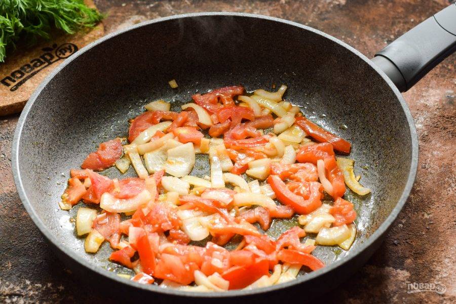 Сковороду разогрейте, смажьте растительным маслом, выложите лук и помидоры, жарьте на небольшом огне 3 минуты.