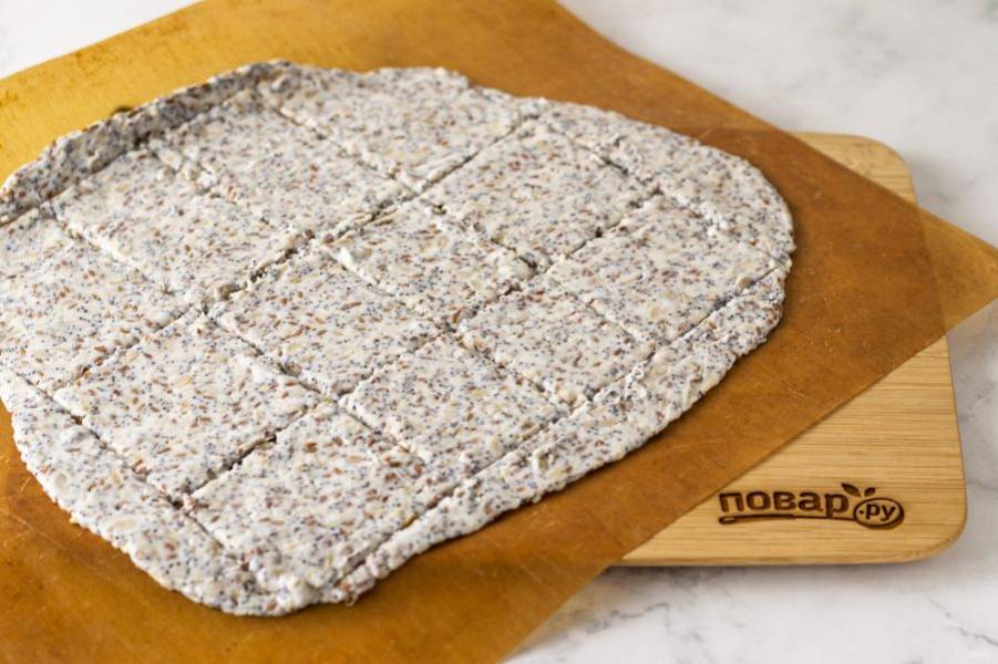 Выложите получившуюся массу ровным слоем на пергамент для выпечки. Ножом разделите хлебцы на квадратики или прямоугольники. Выпекайте 20-25 минут в заранее разогретой до 160 градусов духовке.