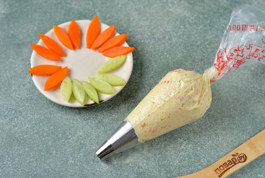 Переложите начинку в кондитерский мешок с круглой насадкой. Морковь и огурец нарежьте тонкими ломтиками, вырежьте из них ушки любой удобной вырубкой для печенья.