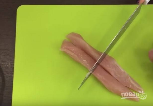 2. Нарежьте филе тонкими полосами, а затем — наполовину. Должны получиться продолговатые кусочки мяса.