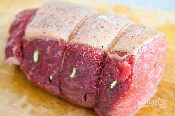 Промойте мясо и оставьте, чтобы оно приобрело комнатную температуру. Затем чеснок порежьте кусочками и нашпигуйте им мясо со всех сторон, делая небольшие надрезы. Свяжите плотно мясо бечевкой или кулинарной нитью в нескольких местах.
