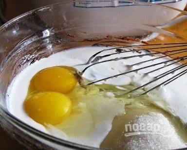 В ту же миску вбейте сырые куриные яйца. К ним влейте жирные сливки (250 мл) и добавьте сметану. Все ингредиенты взбейте венчиком. 