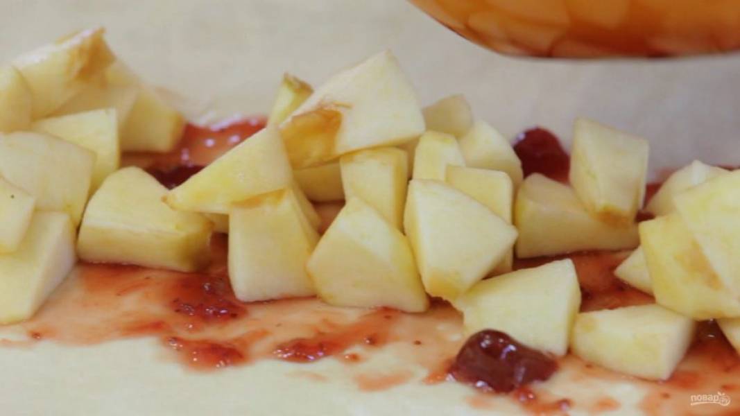 3. Размороженное тесто растяните в прямоугольник. По центру смажьте джемом. Выложите яблоки, орехи и изюм.
