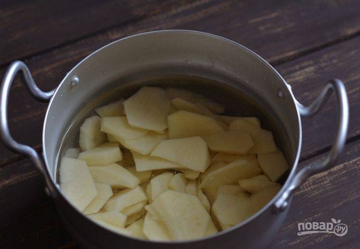 Картофель очистите и вымойте. Нарежьте его на произвольные куски и положите в кастрюлю. Залейте картофель чистой водой и поставьте на плиту. Варите двадцать минут до готовности. 