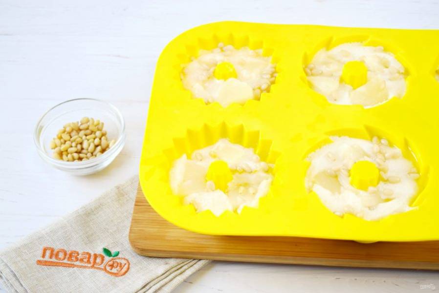 Разлейте массу по силиконовым формочкам, поставьте на 1 час в холодильник. Разложите поверх немного схватившегося желе кусочки ананаса и кедровые орешки. Поставьте десерт  в холодильник до полного застывания.