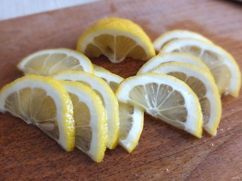 Лимон разрежьте пополам. Удалите косточки. Половинки нарежьте на тонкие ломтики.