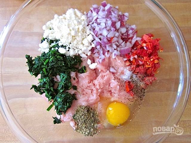 4.	В большую миску выложите готовый индюшиный фарш, измельченный лук и томаты, раскрошите фету, добавьте замороженный шпинат, сушеные специи, соль и яйцо.