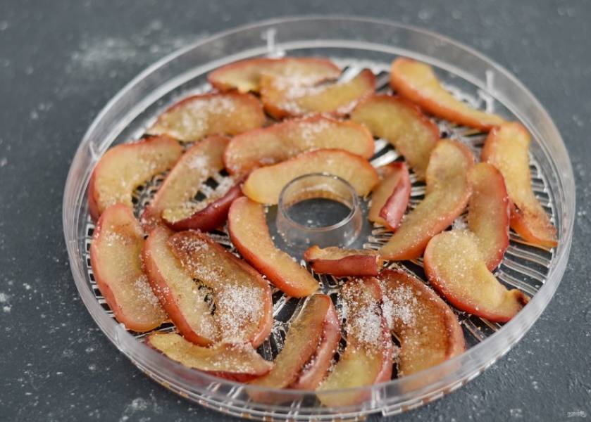 Переложите яблоки в лотки сушилки, сверху посыпьте сахаром. Сушите яблочные дольки 4-6 часов при температуре 60-70 градусов. 