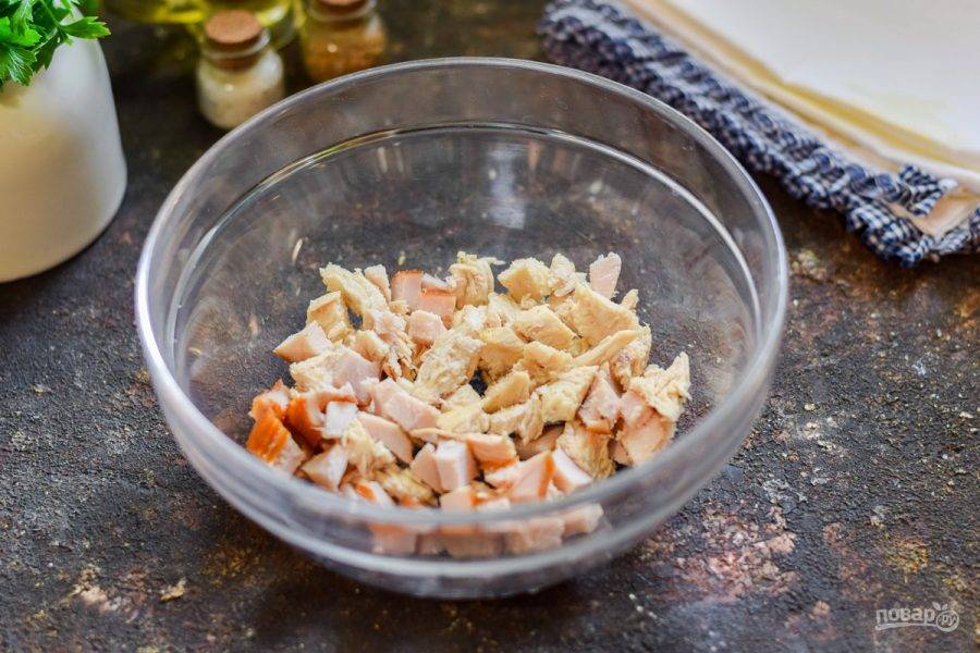 Куриное филе, вареное и копченое, нарежьте небольшими кубиками и переложите в салатник.