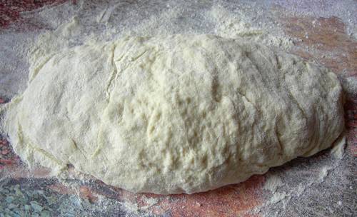 Отдельно смешиваем муку и соду, начинаем постепенно всыпать муку в кефирную массу и замешивать тесто, оно должно получиться мягким и податливым.