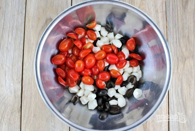 Моцареллу нарежьте маленькими ломтиками, помидоры черри – вдоль пополам, маслины – так же. Положите эти продукты в салатную миску и пока отставьте.