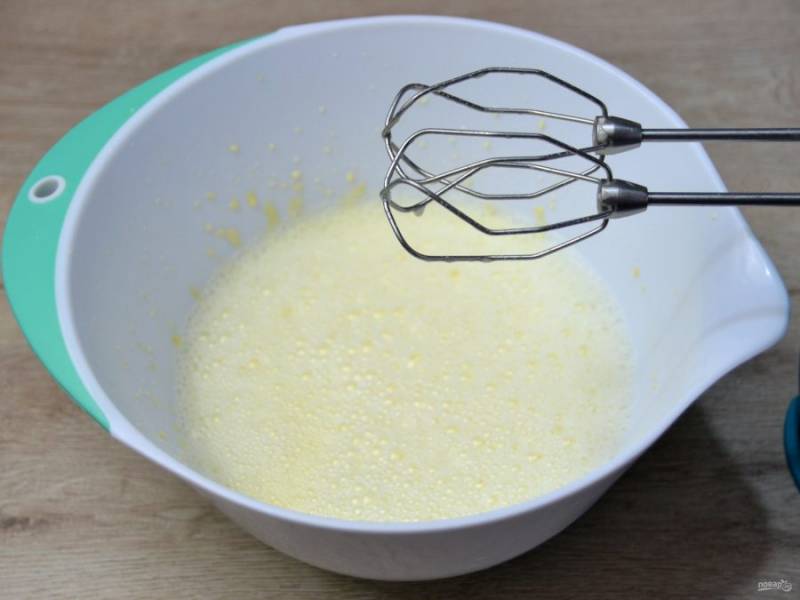 Тонкой струйкой влейте горячие сливки с молоком в желтковую массу, продолжая взбивать.