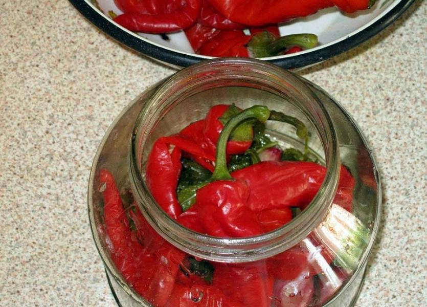 Банки стерилизуем любым удобным для вас способом. Теперь на дно банки выкладываем зелень из маринада и зубчики чеснока, затем аккуратно заполняем ее перцем. Заливаем перец маринадом так, чтобы в банку попали все специи. Прижимаем перец, как бы утрамбовывая его, и доливаем еще маринад под самое горлышко.