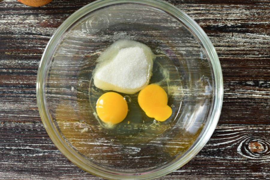В миску вбейте куриные яйца, всыпьте к ним сахар.