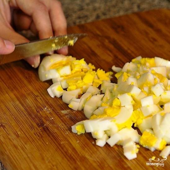 Яйца нарезаем небольшими кубиками и тоже добавляем в салатницу.