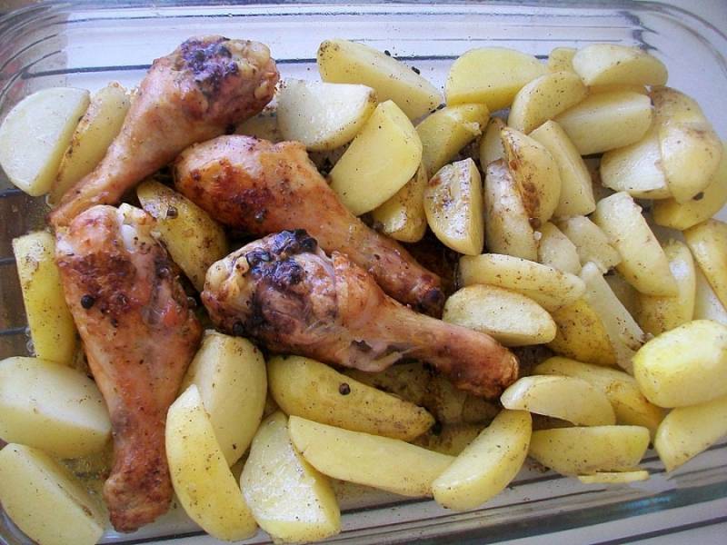 Перекладываем обжаренный картофель к куриным голеням и ставим все в разогретую до 180 градусов духовку примерно на 25-30 минут. 