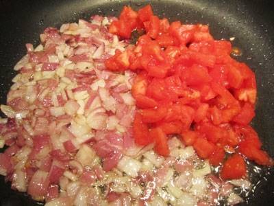 7. К луку отправляем помидоры и выдавленный чеснок. Через 5 минут жарки добавляем измельченные орехи и жарим до готовности.