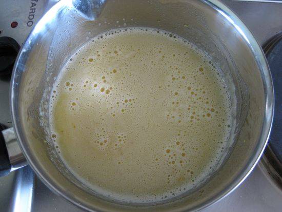 8. Добавьте для дополнительного аромата цедру. Всыпьте сахар, отправьте в сок растопленное сливочное масло. Поставьте крем на огонь. 