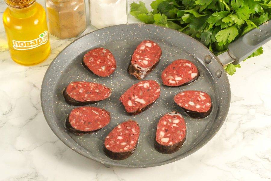 Нарежьте кровяную колбасу ломтиками. Прогрейте сковороду с растительным маслом и выложите в нее ломтики колбасы. Обжарьте примерно 1-2 минуты.