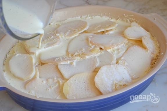 Присыпьте сыром и залейте сливками. Отправляйте форму с картофелем в разогретую до 200 градусов духовку на 1 час.