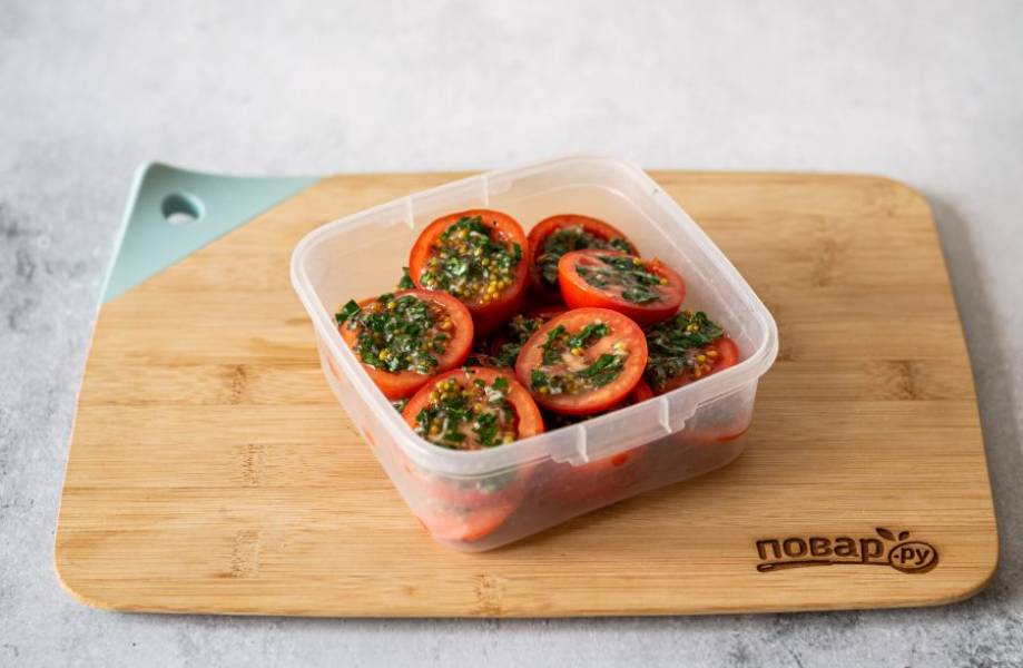 Выложите помидоры в плотно закрывающуюся емкость. На каждый кружочек выкладывайте по заправке из зелени и чеснока. Уберите в холодильник на полчаса.