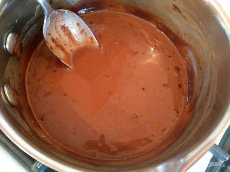 Добавьте сахарный песок и какао-порошок, хорошо перемешайте и поместите ковш на плиту. На умеренном огне прогрейте массу до загустения, постоянно помешивая её.